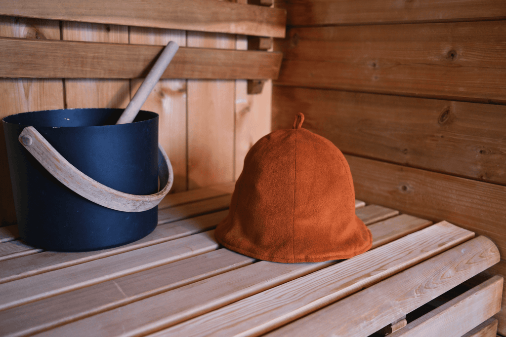 Sauna hat next to sauna bucket in a sauna hat