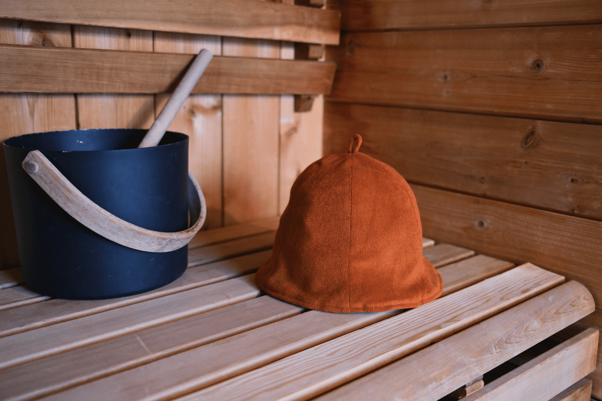 Sauna hat next to sauna bucket in a sauna hat