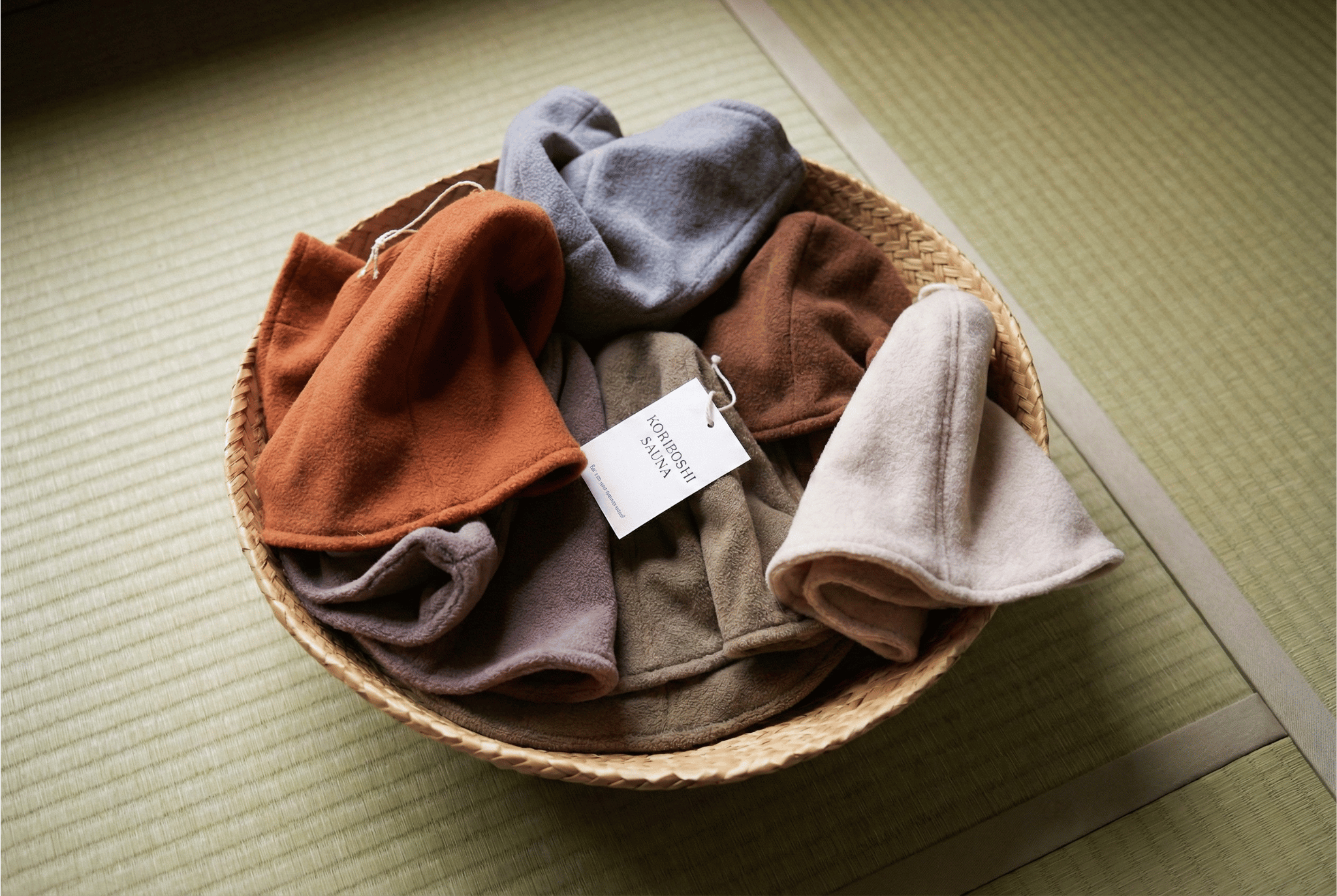 Woven basket with folded clothes on a light wooden floor
